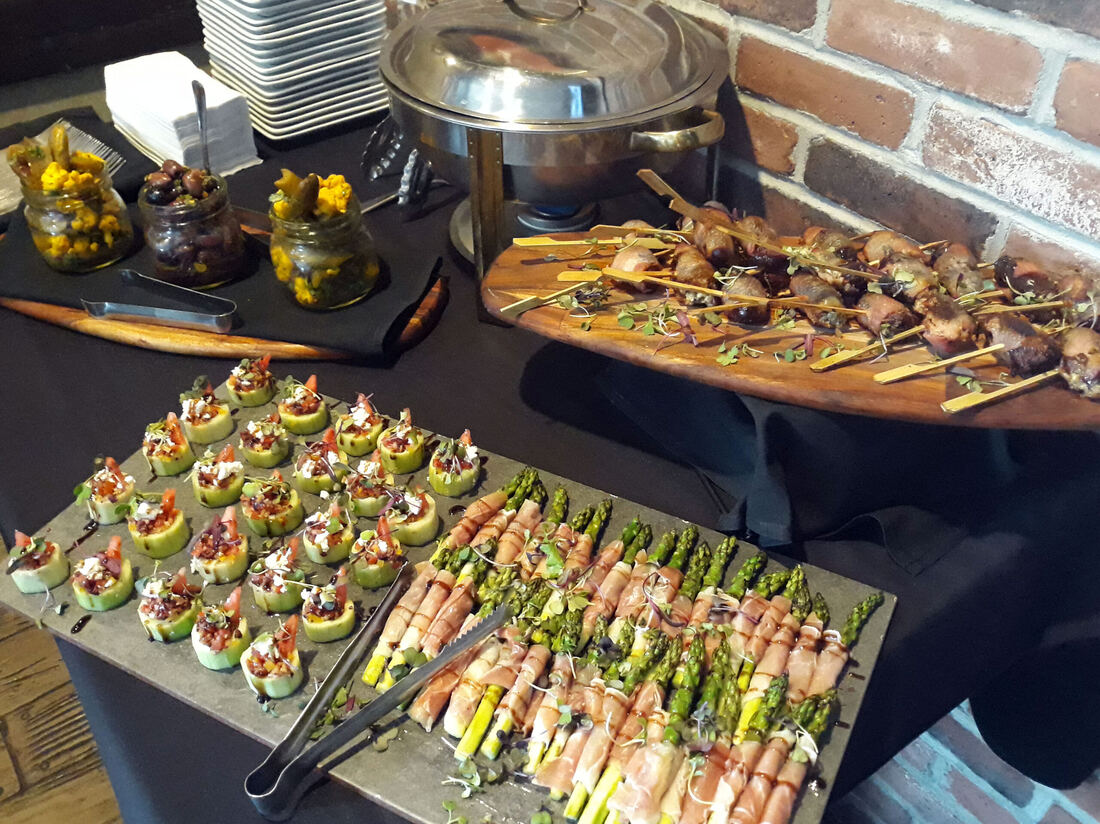 Passed hors d'oeuvres display with prosciutto-wrapped asparagus and skewers